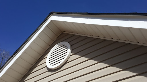 A white roof vent on a tan house.